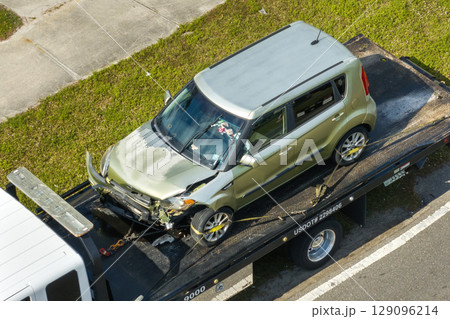 Car accident on American street. Tow truck picking up destroyed car and emergency services helping victims of vehicle crash on road in USA 129096214