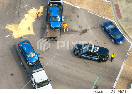 Car accident on American street. Tow truck picking up destroyed car and emergency services helping victims of vehicle crash on road in USA 129096215