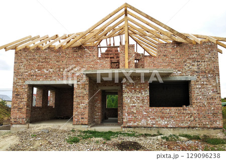 Brick residential house with wooden roof under construction. 129096238