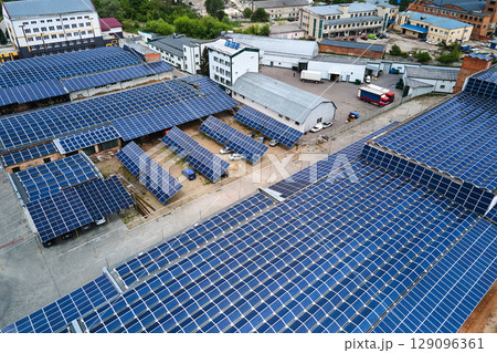 Aerial view of solar power plant with blue photovoltaic panels mounted on industrial building roof for producing green ecological electricity. Production of sustainable energy concept. Aerial view of solar power plant with blue photovoltaic panels mounted on industrial building roof for producing green ecological electricity. Production of sustainable energy concept. 129096361