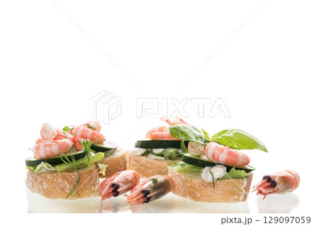 Small canapes with shrimps, salad and cucumbers on a white background 129097059