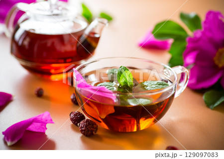 Top view of brewed rosehip tea with mint in glassware on brown background 129097083