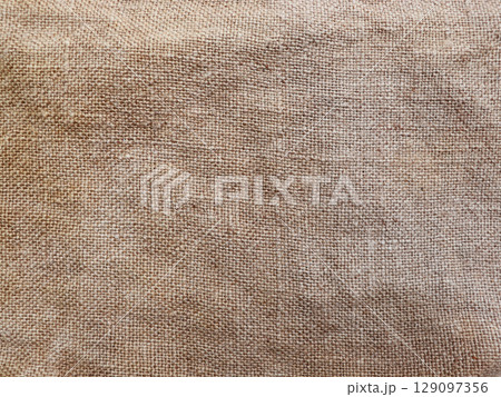 Rural texture of sackcloth. Background of very coarse, rough fabric woven made of flax, jute or hemp. Burlap bag material. Design element. 129097356
