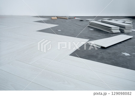 A man lays a quartz laminate on the floor. Renovation, Installation of French herringbone 129098082
