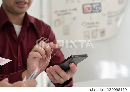 UX and UI Design Collaboration. Team discussing mobile app interface on smartphone. 129098159