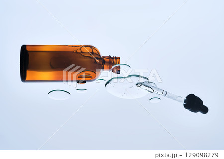 A bottle of cosmetic product with a serum texture. View from below. 129098279