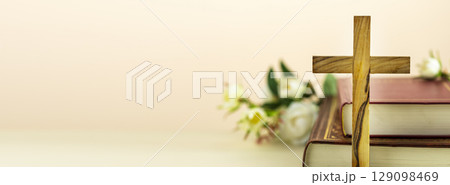 Religion banner with wooden cross with closed red Christian bibles with white flowers on a light gradient background with copy space. Easter holiday. Christian religion background. Front view Religion banner with wooden cross with closed red Christian bibles with white flowers on a light gradient background with copy space. Easter holiday. Christian religion background. Front view 129098469