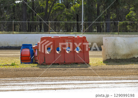 An industrial plastic safety barrier at a dirt race track 129099198
