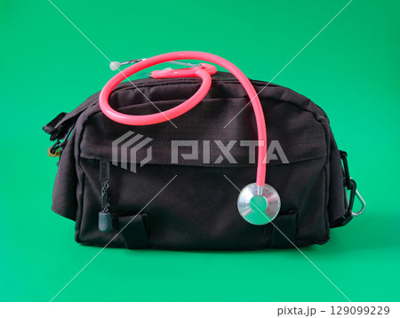 A doctors bag with a stethoscope looped around the handle . 129099229