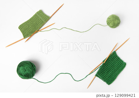 Green knitted wool on gray background with knitting needles for knitting warm clothes and hobbies needlework 129099421