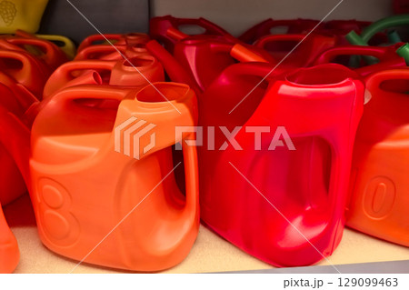 Colorful plastic containers lined up on a shelf in a store Colorful plastic containers lined up on a shelf in a store 129099463