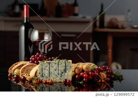 Gorgonzola cheese with ciabatta, walnuts, grapes, and red wine on a kitchen table. 129099572