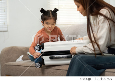 Family Bonding. Child and mother joyfully packing for travel at home. 129100705
