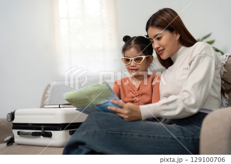 Travel Excitement. Mother and daughter looking at a map together before their trip. 129100706
