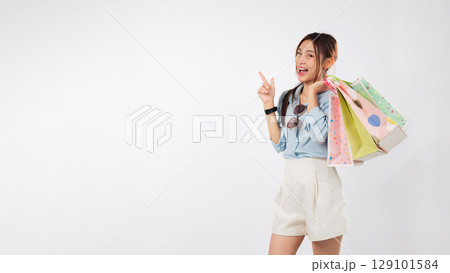 Happy young asian woman pointing finger, excited by promotion after shopping, a charming girl presenting offers for shoppers with mockup shopping bags, isolated studio white background 129101584