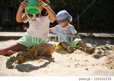 Children Playing and Building in a Sunny Sandbox During Summer Children Playing and Building in a Sunny Sandbox During Summer 129102259