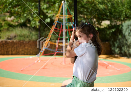 Young Girl Enjoying Fun Time at a Colorful Playground on a Bright Summer Day Young Girl Enjoying Fun Time at a Colorful Playground on a Bright Summer Day 129102290