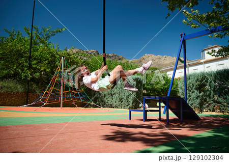 Child Enjoying Playtime on Swing in Vibrant Playground Child Enjoying Playtime on Swing in Vibrant Playground 129102304