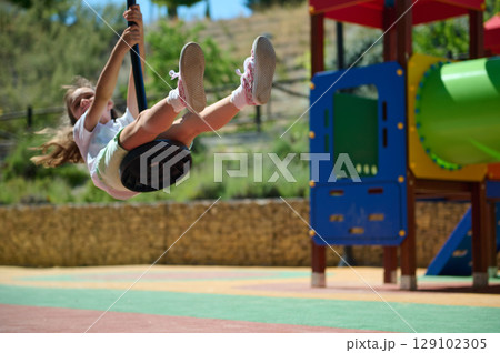 Young Girl Enjoying Playground Swing on a Bright Summer Day 129102305