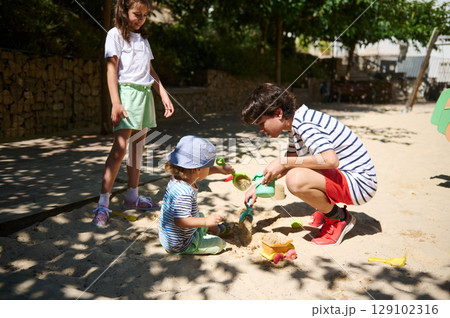 Children Playing Together in a Sunny Outdoor Playground with Sand Toys Children Playing Together in a Sunny Outdoor Playground with Sand Toys 129102316