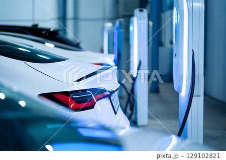 Modern electric vehicles charging at sleek station, futuristic city mobility with neon-lit charging ports 129102821