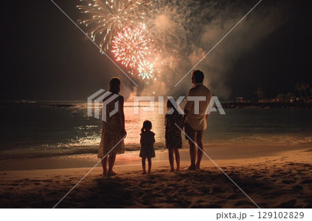 真夏の夜に並んで花火を見上げる家族｜海辺の静けさと感動の光景 129102829