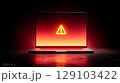 Laptop showing warning alert sign on red background in dark room 129103422