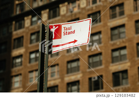 Urban taxi stand sign prominently displays pictogram of person and directional arrow. Bright daylight enhances informative and functional mood of city street setting. Urban taxi stand sign prominently displays pictogram of person and directional arrow. Bright daylight enhances informative and functional mood of city street setting. 129103482