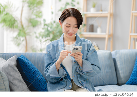 リビングでスマホを見るミドルの女性 リビングでスマホを見るミドルの女性 129104514