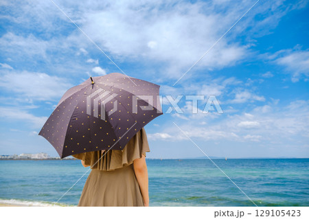 日傘をさして海を眺める女性 129105423