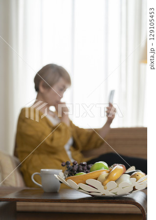 ソファーに座りスマホを手にする高齢女性 ソファーに座りスマホを手にする高齢女性 129105453
