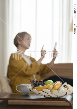ソファーに座りスマホを手にする高齢女性 ソファーに座りスマホを手にする高齢女性 129105454