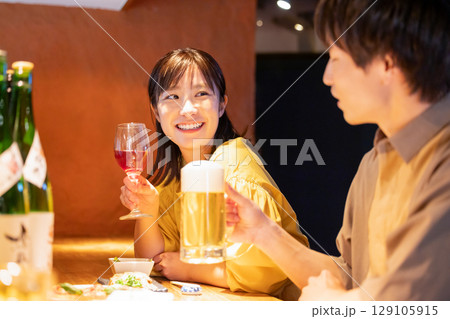 居酒屋でお酒を飲んでる男女 129105915
