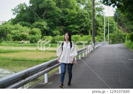 田舎町を歩く女性 129107880