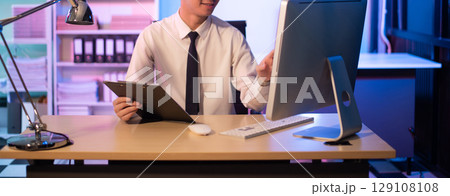 Businessman drinking coffee to get some energy for working overtime sitting at desk using computer and doing overtime 129108108