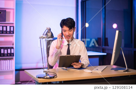 Businessman drinking coffee to get some energy for working overtime sitting at desk using computer and doing overtime 129108114