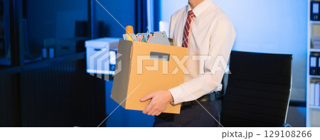 Asian male professional packing office belongings in a box, representing themes of resignation, new job, or relocation. Office, job, career change 129108266