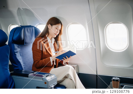 Asian woman sitting in a seat in airplane and looking out the window going on a trip vacation travel concept.Capture the allure Asian woman sitting in a seat in airplane and looking out the window going on a trip vacation travel concept.Capture the allure 129108776