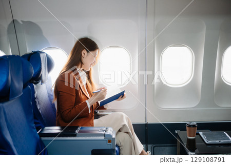 Asian woman sitting in a seat in airplane and looking out the window going on a trip vacation travel concept.Capture the allure Asian woman sitting in a seat in airplane and looking out the window going on a trip vacation travel concept.Capture the allure 129108791