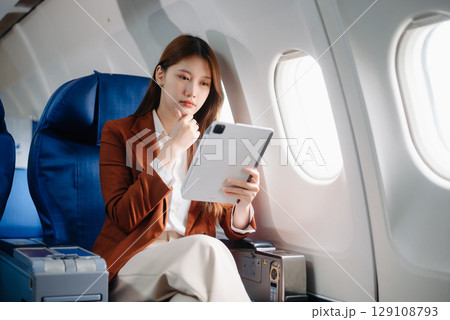 Asian woman sitting in a seat in airplane and looking out the window going on a trip vacation travel concept.Capture the allure 129108793