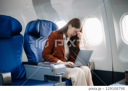 Asian woman sitting in a seat in airplane and looking out the window going on a trip vacation travel concept.Capture the allure 129108798