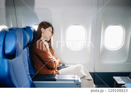 Photo of a frustrated woman sitting on an airplane with her head in her hands. Asian woman sitting in a seat Photo of a frustrated woman sitting on an airplane with her head in her hands. Asian woman sitting in a seat 129108823
