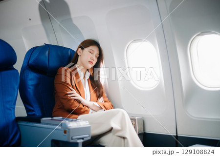 Photo of a frustrated woman sitting on an airplane with her head in her hands. Asian woman sitting in a seat 129108824
