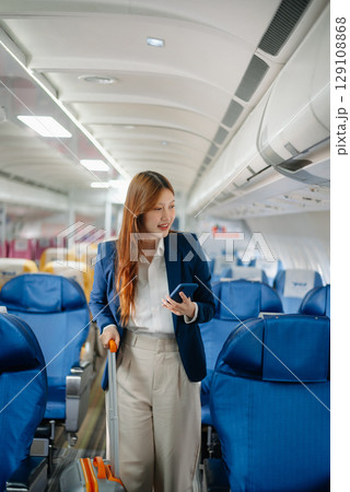 Attractive Asian female passenger of airplane sitting in comfortable seat while working laptop and tablet with mock up area using wireless connection. 129108868