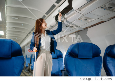 Attractive Asian female passenger of airplane sitting in comfortable seat while working laptop and tablet with mock up area using wireless connection. 129108869