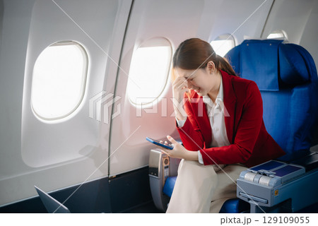 Photo of a frustrated woman sitting on an airplane with her head in her hands. Asian woman sitting in a seat Photo of a frustrated woman sitting on an airplane with her head in her hands. Asian woman sitting in a seat 129109055
