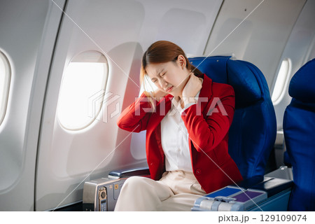 Photo of a frustrated woman sitting on an airplane with her head in her hands. Asian woman sitting in a seat 129109074