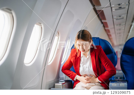 Photo of a frustrated woman sitting on an airplane with her head in her hands. Asian woman sitting in a seat 129109075