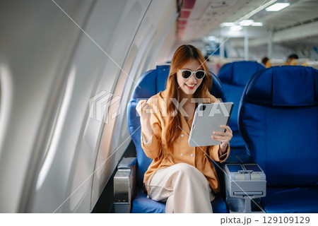 Asian Woman Working on Tablet During in first class, multitasking with Flight Travel in style, work Asian Woman Working on Tablet During in first class, multitasking with Flight Travel in style, work 129109129