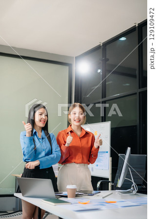 Two Asian businesswoman and man discuss investment project working and planning strategy with tablet laptop computer 129109472